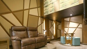 A modern living room with a leather sofa, a wooden coffee table, and a light blue ottoman. - Hotel Ava Malate, Manila (Manila)