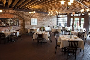 Un restaurante con paredes de ladrillo, vigas de madera y mesas preparadas para comer.