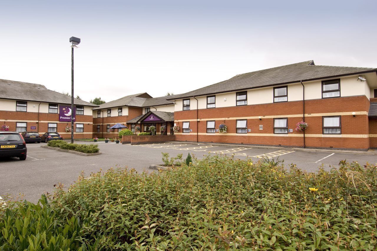 A hotel with a parking lot, a covered entrance, and a sign indicating Premier Inn.
