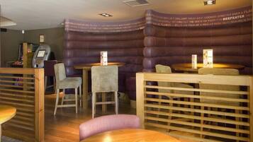 A restaurant with cushioned booths, wooden tables, and a menu stand.