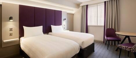 A hotel room with two beds, a desk, and a chair.