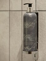 Dispensador de gel de ducha y lavado corporal de lujo Baylis & Harding Elements, fijado a una pared de azulejos.