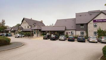 Un hotel con varias edificaciones, un estacionamiento con varios automóviles y un letrero que dice 'Premier Inn'.