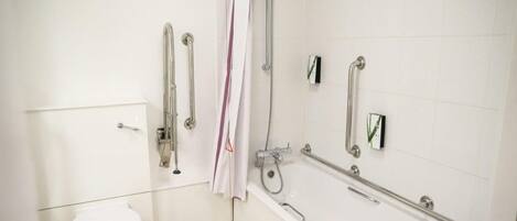 A bathroom with a white toilet, a shower with grab bars, and a bathtub.