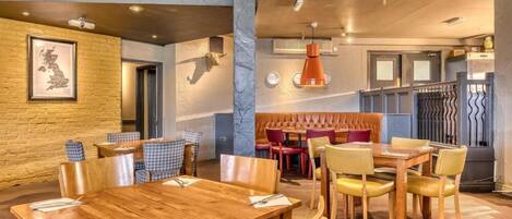 A restaurant with wooden tables and chairs, a bar area, and a seating section with cushioned booths.