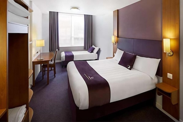 A hotel room with a large bed, a smaller bed, a desk, and a chair. - Premier Inn Bedford Priory Marina (Bedford)