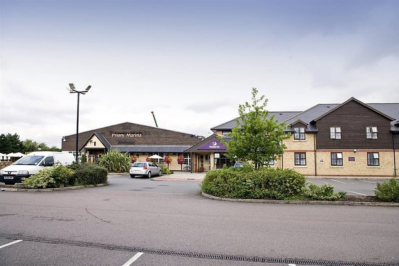 A Priory Marina hotel with a parking lot, a white van, and a car parked in front.
