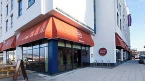 Un bâtiment doté d’un auvent rouge, de grandes fenêtres et d’une enseigne indiquant « Premier Inn ».