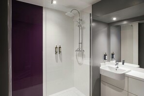 A modern bathroom with a glass shower enclosure, a white sink, and a large mirror. - Premier Inn Weston Super-mare (Weston-super-Mare)