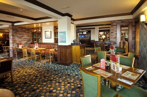 A hotel lobby with a patterned carpet, wooden furniture, and a reception desk. - Premier Inn Weston Super-mare (Weston-super-Mare)