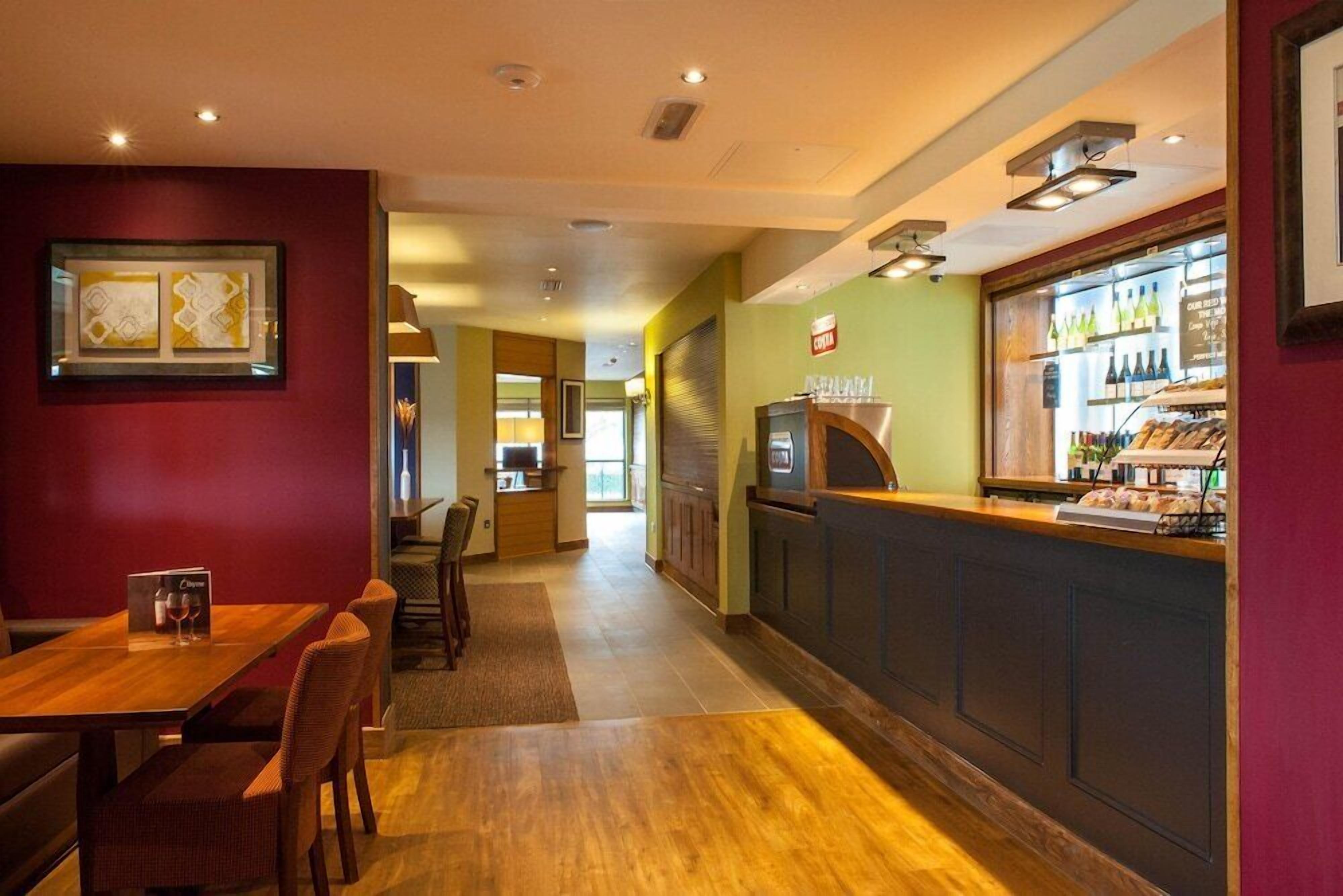 Un restaurante con piso de madera, una barra con menú y una zona de estar con sillas y una mesa.