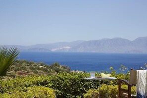 Una mesa con una laptop y un tazón, con vistas a un paisaje costero y montañas.