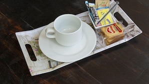 Una bandeja con una taza blanca, un sándwich y algunos alimentos envasados.