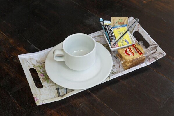 A tray with a white cup, a sandwich, and some packaged food items. - Habana Vieja Hotel (Medellín)