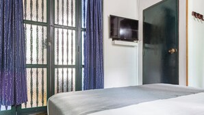 A bedroom with a bed, a television on the wall, and a door. - Habana Vieja Hotel (Medellín)