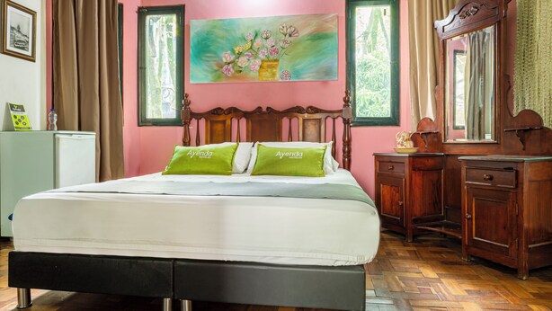 A bedroom with a bed, a painting, a dresser, and a mirror. - Habana Vieja Hotel (Medellín)