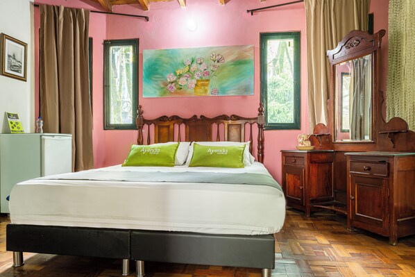 A bedroom with a bed, a painting, a dresser, and a mirror. - Habana Vieja Hotel (Medellín)
