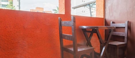 Un coin de pièce avec un mur rouge, une fenêtre et deux chaises en bois.