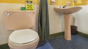 A bathroom with a toilet, sink, and a green sign on the wall. - Habana Vieja Hotel (Medellín)