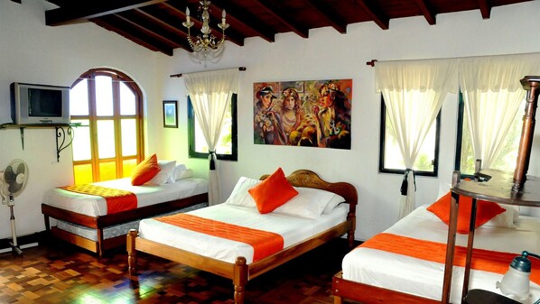 Una habitación de hotel con dos camas, un televisor, un cuadro y un ventilador.