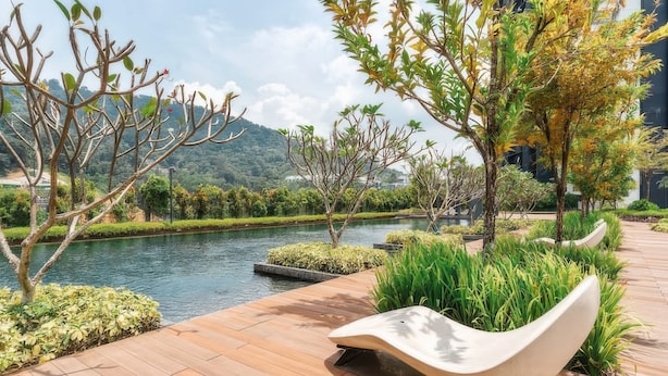 A serene outdoor area with a wooden deck, a curved white bench, and a water feature. - Staycation KL - The Ridge Apartments (Kuala Lumpur)