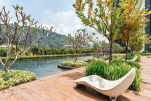 A serene outdoor area with a wooden deck, a curved white bench, and a water feature. - Staycation KL - The Ridge Apartments (Kuala Lumpur)
