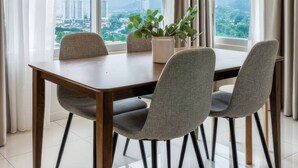 A dining area with a table, four chairs, a hanging light fixture, and a view of buildings through large windows. - Staycation KL - The Ridge Apartments (Kuala Lumpur)
