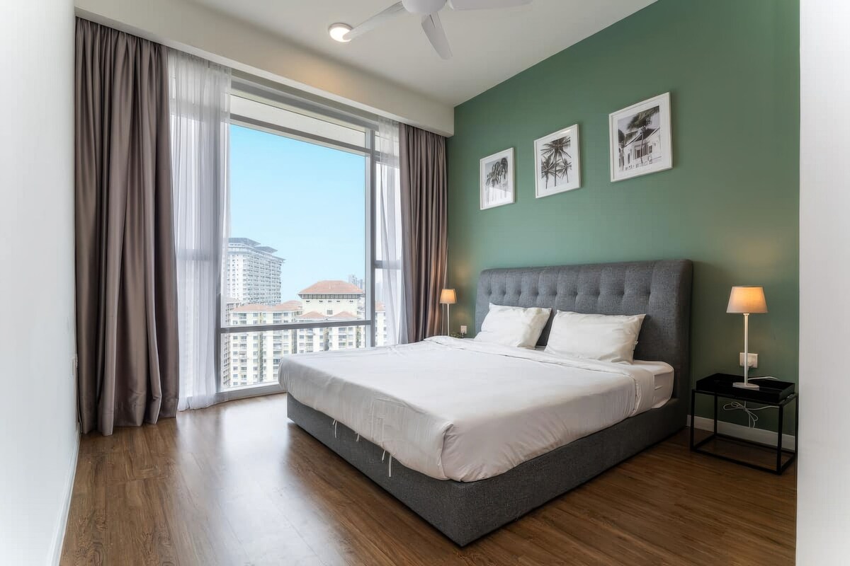 A modern hotel room with a large bed, a view of the city, and artwork on the walls.