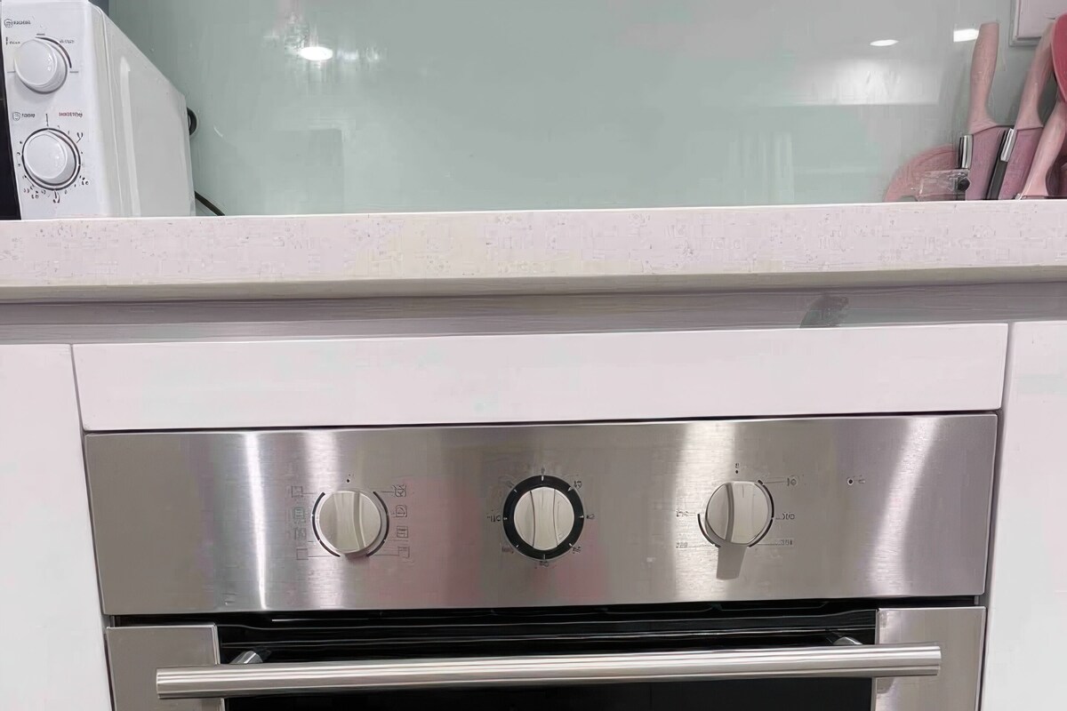 A stainless steel oven with three knobs and a digital display, built into a kitchen counter.