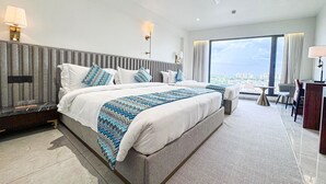A modern hotel room with a large bed, a desk, and a view of the city. - Hotel Veritas Grand (Sanand)