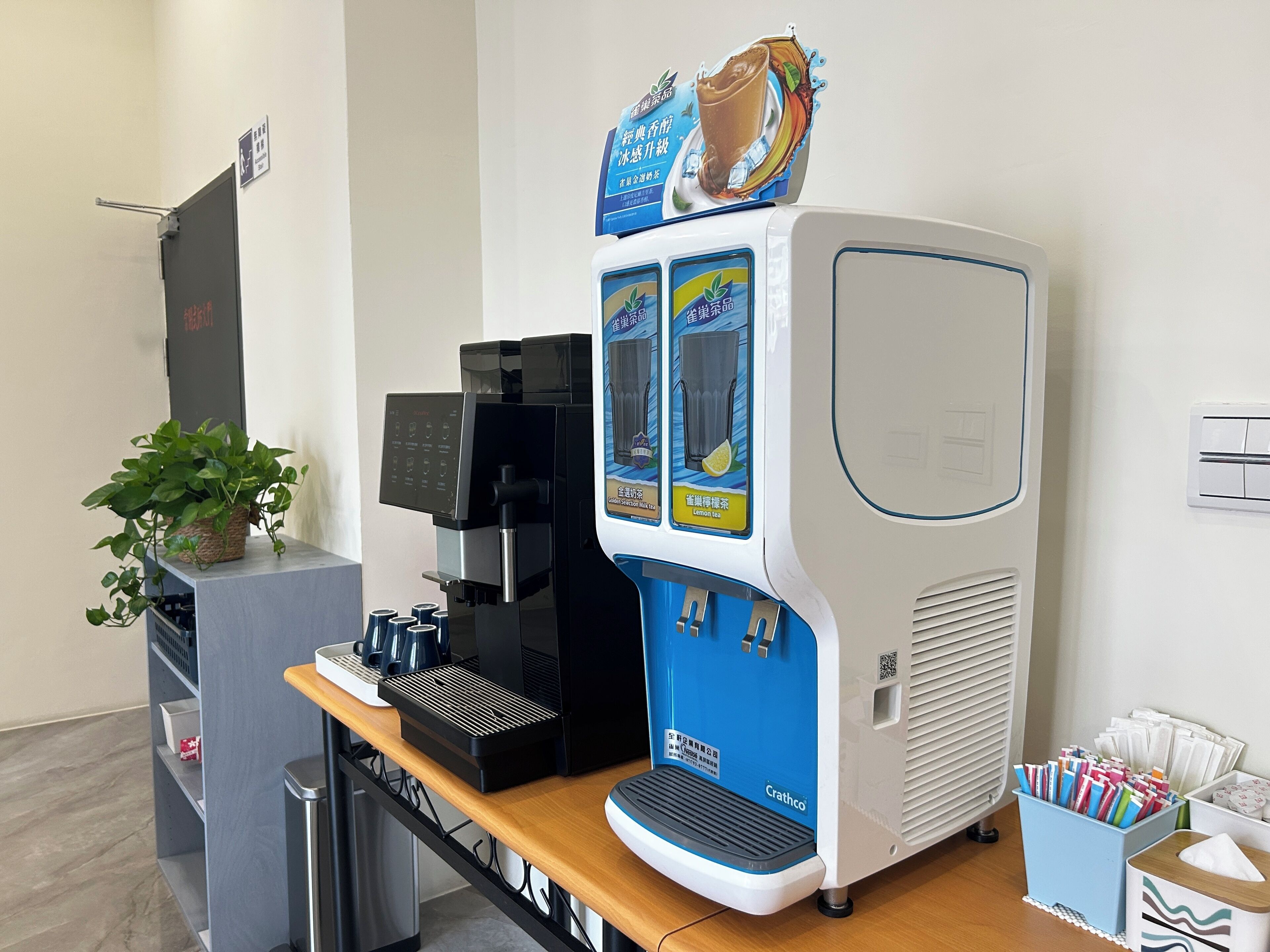 A coffee machine with a blue and white design, a small plant, and a trash bin.