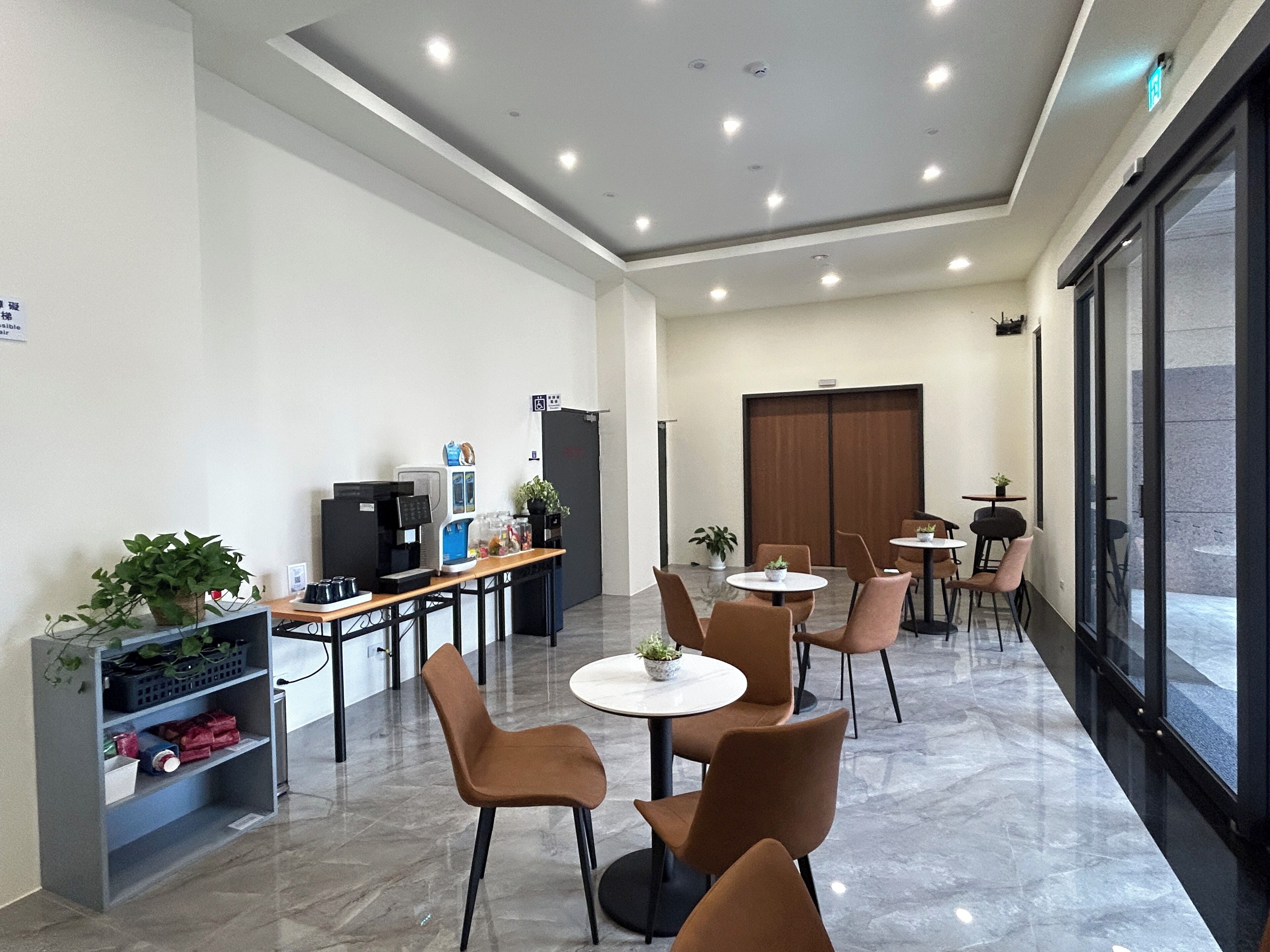 A modern indoor space with seating, a coffee machine, and a large window.