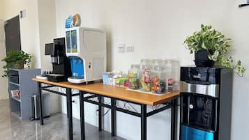 A coffee station with a coffee machine, a water dispenser, and a variety of snacks.