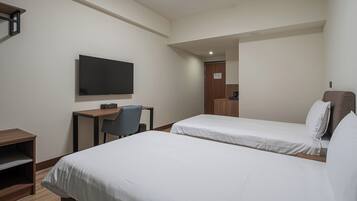 Habitación de hotel con dos camas, un escritorio, una silla, un televisor y una kitchenette pequeña.