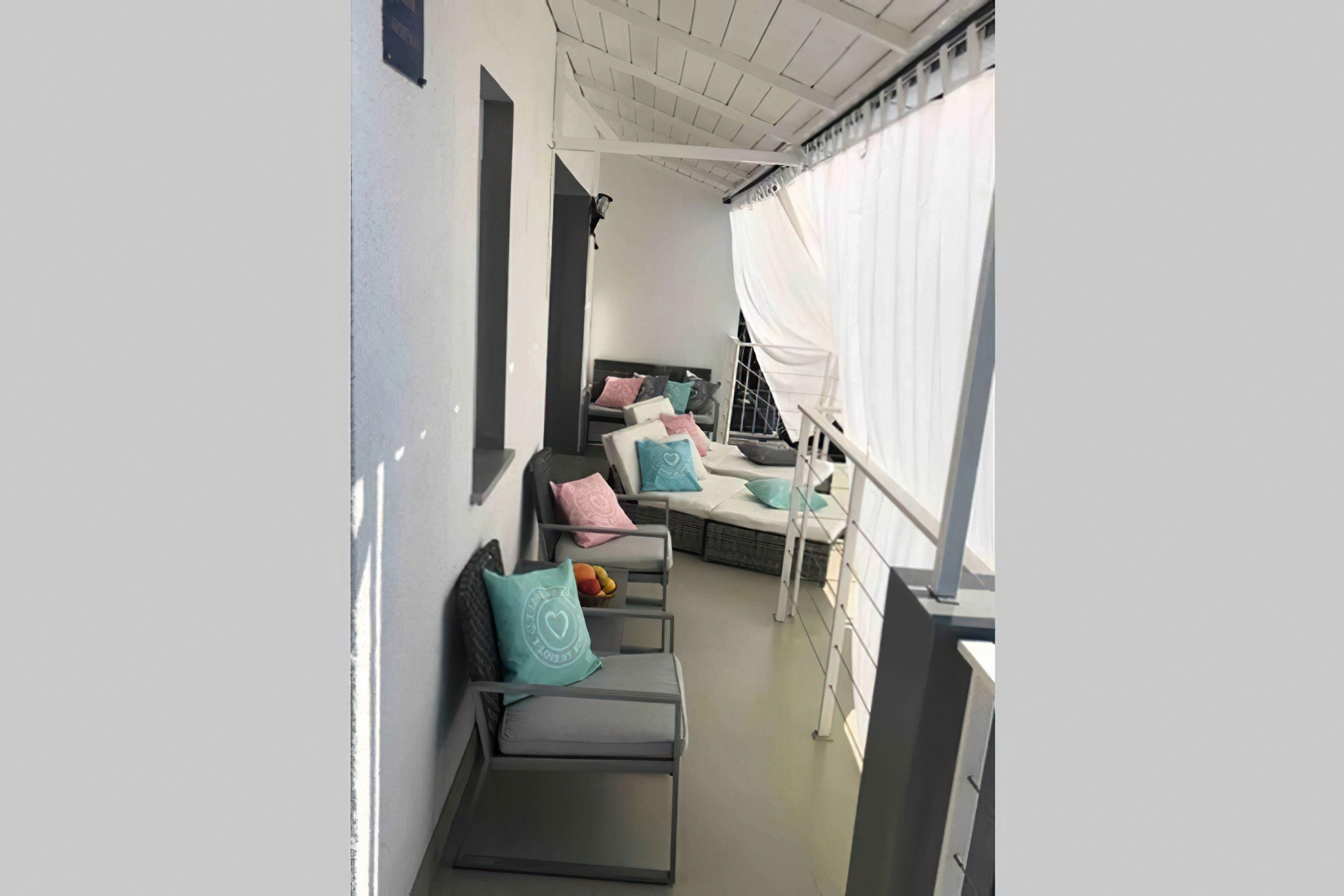 A narrow corridor with a row of grey cushioned seating areas, each with a pillow.