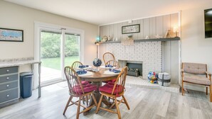 A dining area with a round table, wooden chairs, and a fireplace.