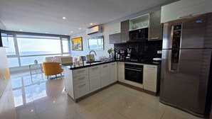 A modern kitchen with a large island, stainless steel appliances, and a view of the ocean.