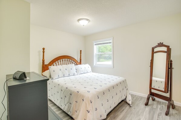 Un dormitorio con cama, cómoda, espejo y ventana.