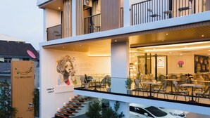 Een modern gebouw met een café op de begane grond, een trap die naar de bovenverdiepingen leidt, en een auto voor de deur.