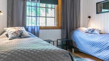 Une chambre avec deux lits, une fenêtre avec des rideaux, une table de chevet et une lampe fixée au mur.