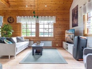 A cozy cabin interior with a sofa, a coffee table, a TV, and a large window. - Hanhenpesä by Interhome (Rautalampi)