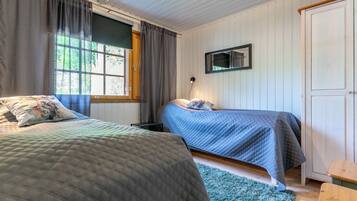 Une chambre avec deux lits, une fenêtre avec des rideaux, un miroir et une porte en bois.