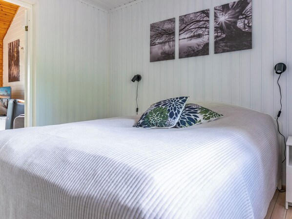 Ein Schlafzimmer mit Bett, Nachttisch, Lampe und Wandbildern.