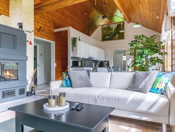 A cozy living room with a fireplace, a sofa, and a coffee table. - Hanhenpesä by Interhome (Rautalampi)