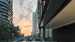 A modern outdoor seating area with benches and a view of a high-rise building. - Ciao Mossaz Suites Luxury Apartments (Petaling Jaya)