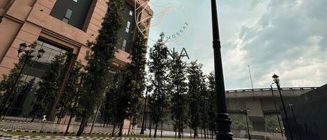 Un edificio alto con un diseño arquitectónico moderno, pavimento a cuadros y una farola.