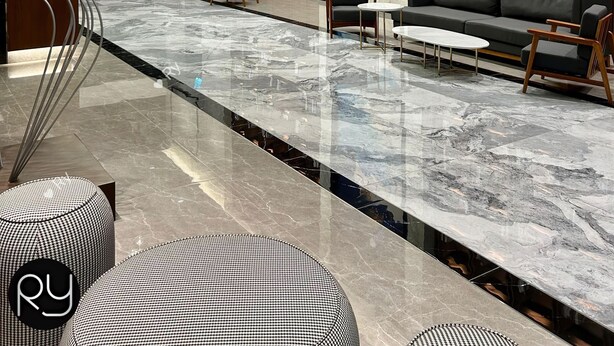 A modern lobby with a marble floor, a large bookshelf, a sofa, and a unique chandelier. - Ciao Mossaz Suites Luxury Apartments (Petaling Jaya)