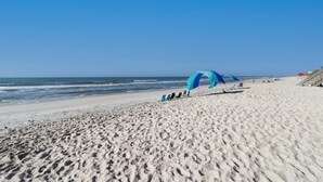Une plage dotée d’un grand parasol bleu et de chaises de plage.