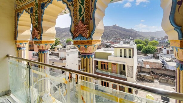 A balcony with ornate arches and a view of a cityscape with buildings and a mountain in the distance. - Hotel Amer Classic (Amer)