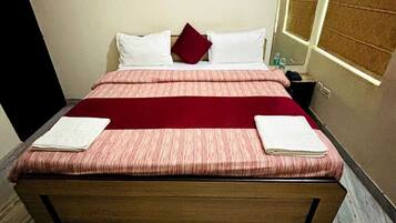 A bed with a wooden frame, a red and white bedspread, and two white pillows.